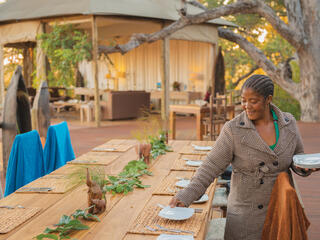 Catherine Mafumelo sets plates on an outdoor table