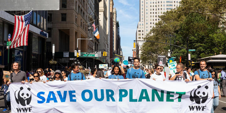 People marching down a New York City street holding "Save Our Planet" banner