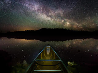 Night photo of stars above the prow of a canoe