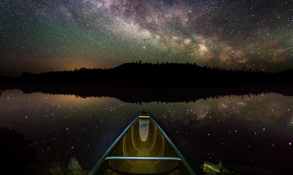 Night photo of stars above the prow of a canoe