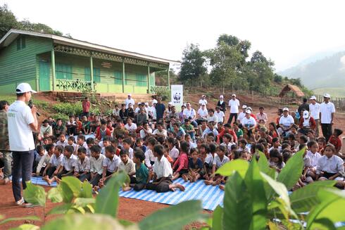 Local community members in Laos sit on blankets in the village common area laid out to discuss a tree planting and forest management program 