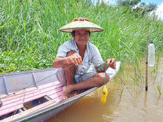 Man in canoe holds pinger device attached to net