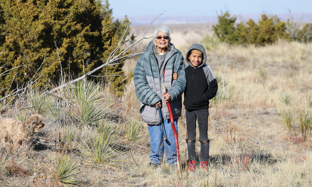 Older woman and child standing amongst scrub plants